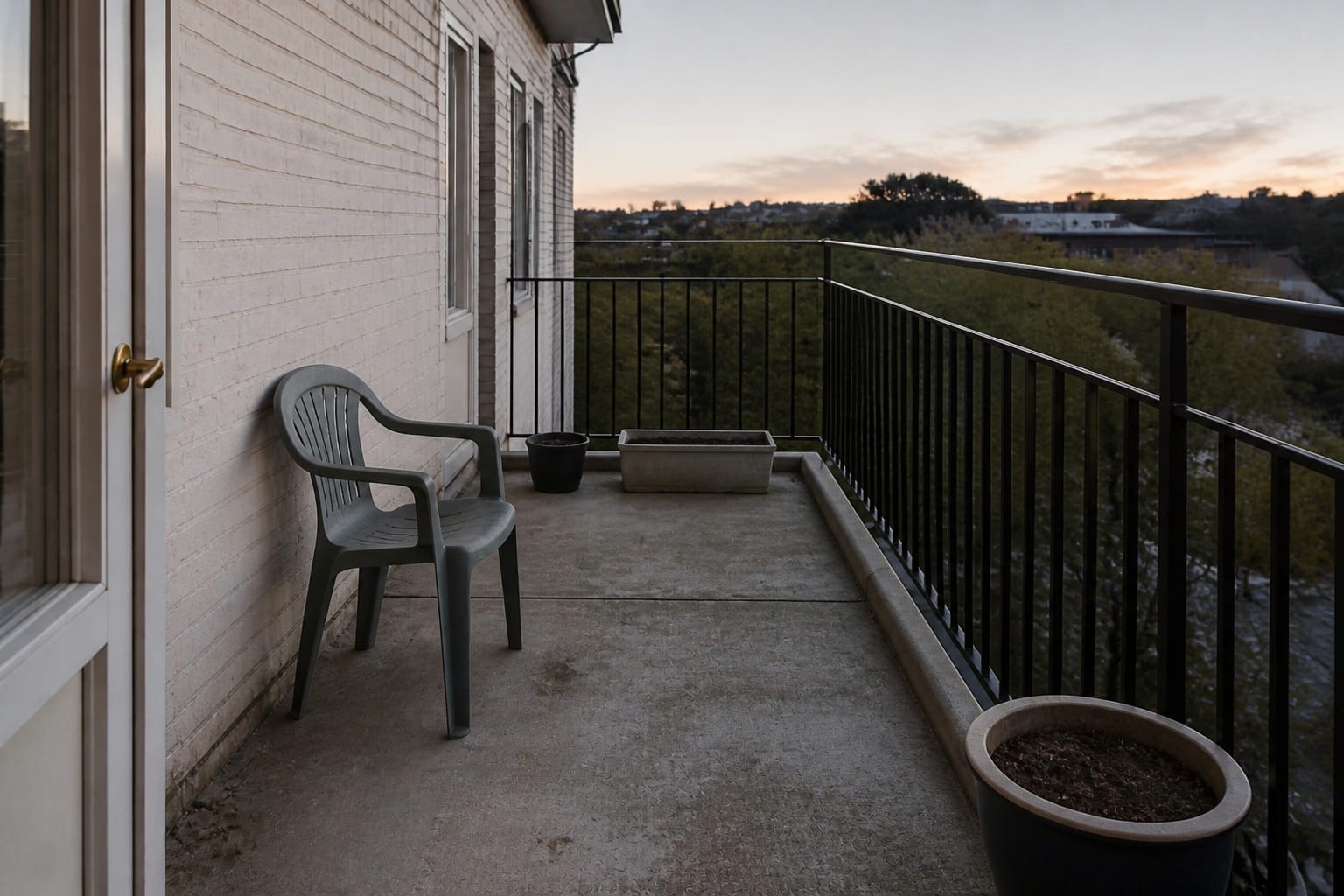 underused apartment balcony with bare concrete floor, one mismatched chair, exposed railing, scattered pots, and no clear seating zone.