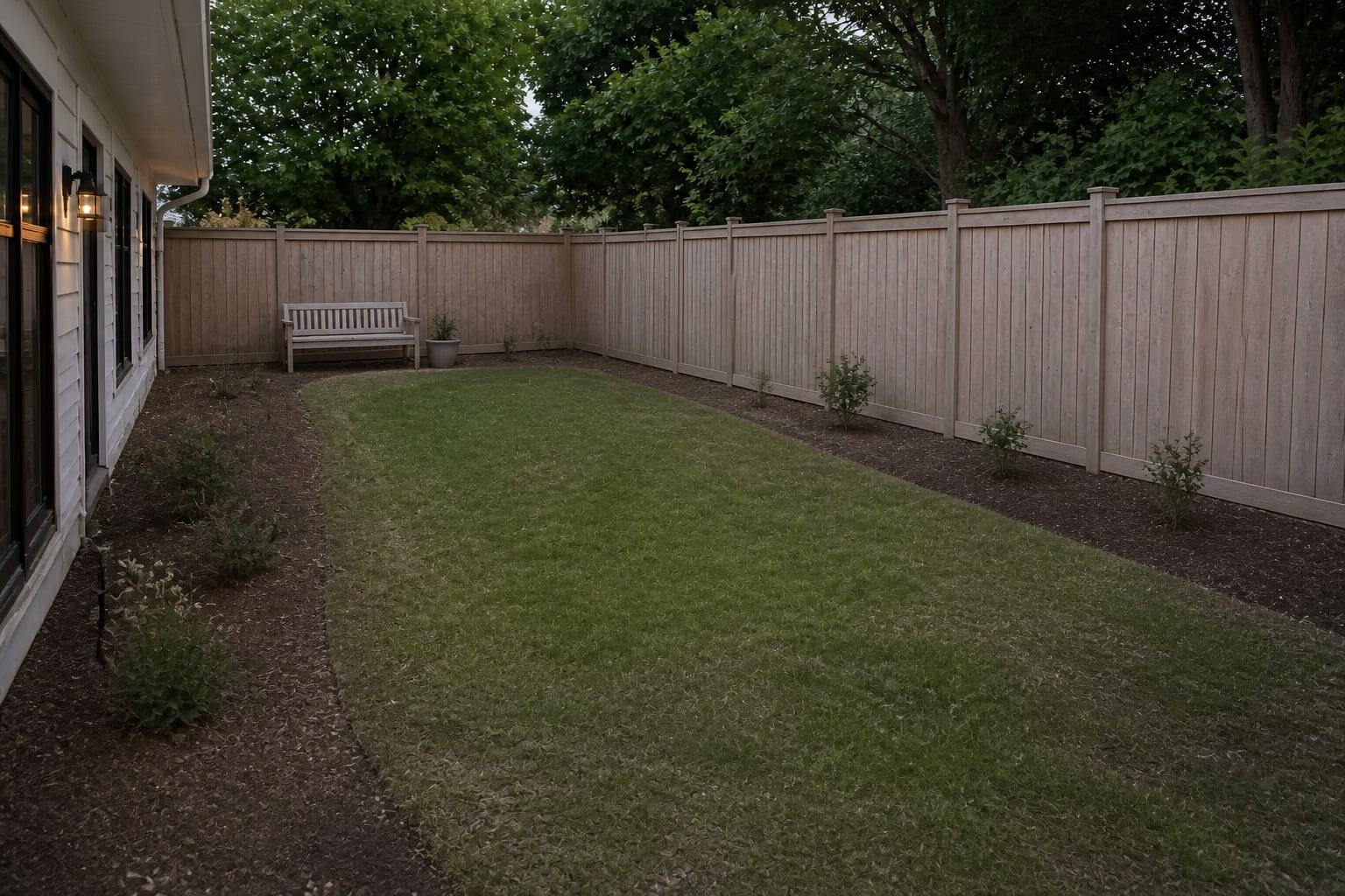 under-designed garden with plain lawn, bare fence line, thin border, and no defined path or planting rhythm