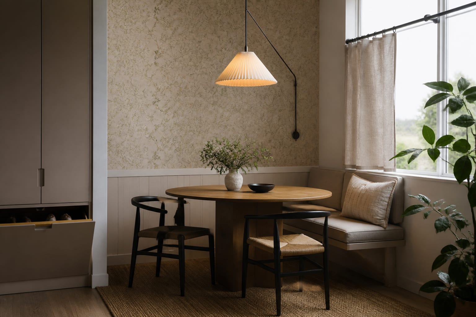 rental dining nook with removable wallpaper, round table, plug-in pendant, closed shoe storage, and curtains mounted high