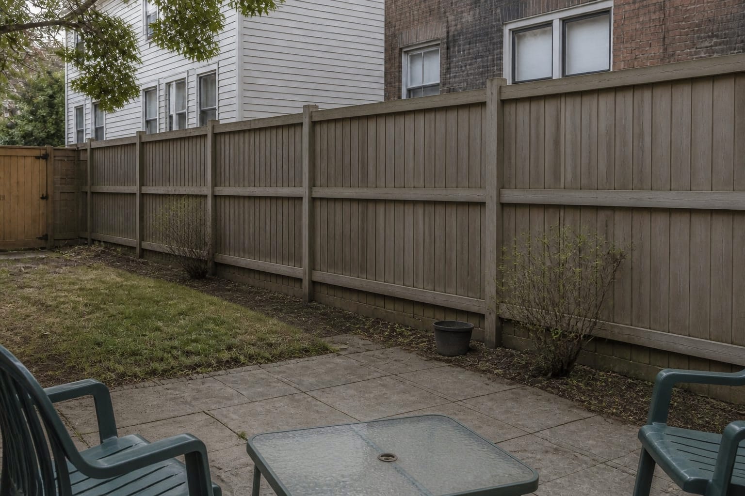 under designed fence line with exposed neighbors, patchy planting, plain boards, and no privacy screen strategy