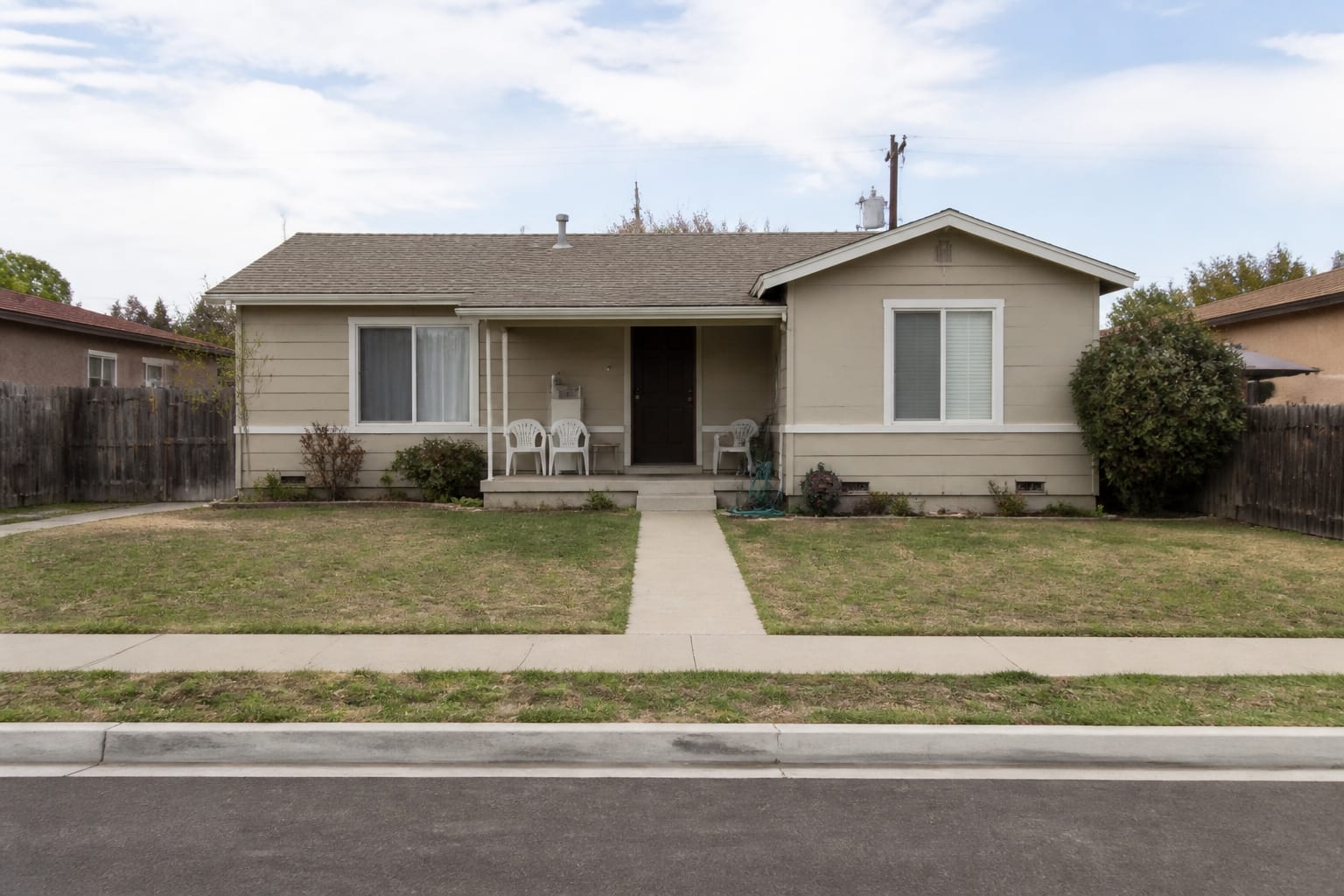 under designed front yard with narrow walkway, plain lawn, thin mulch strip, small shrubs, exposed foundation, and weak porch focus.