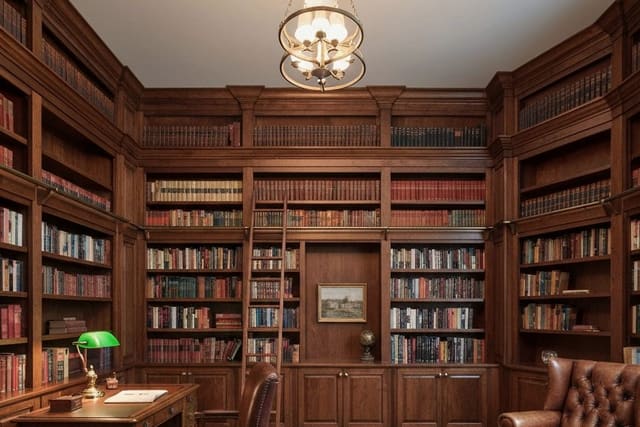 warm home library with built in shelves, a deep reading chair, brass lamp, wool rug, and calm wall color in a bonus room