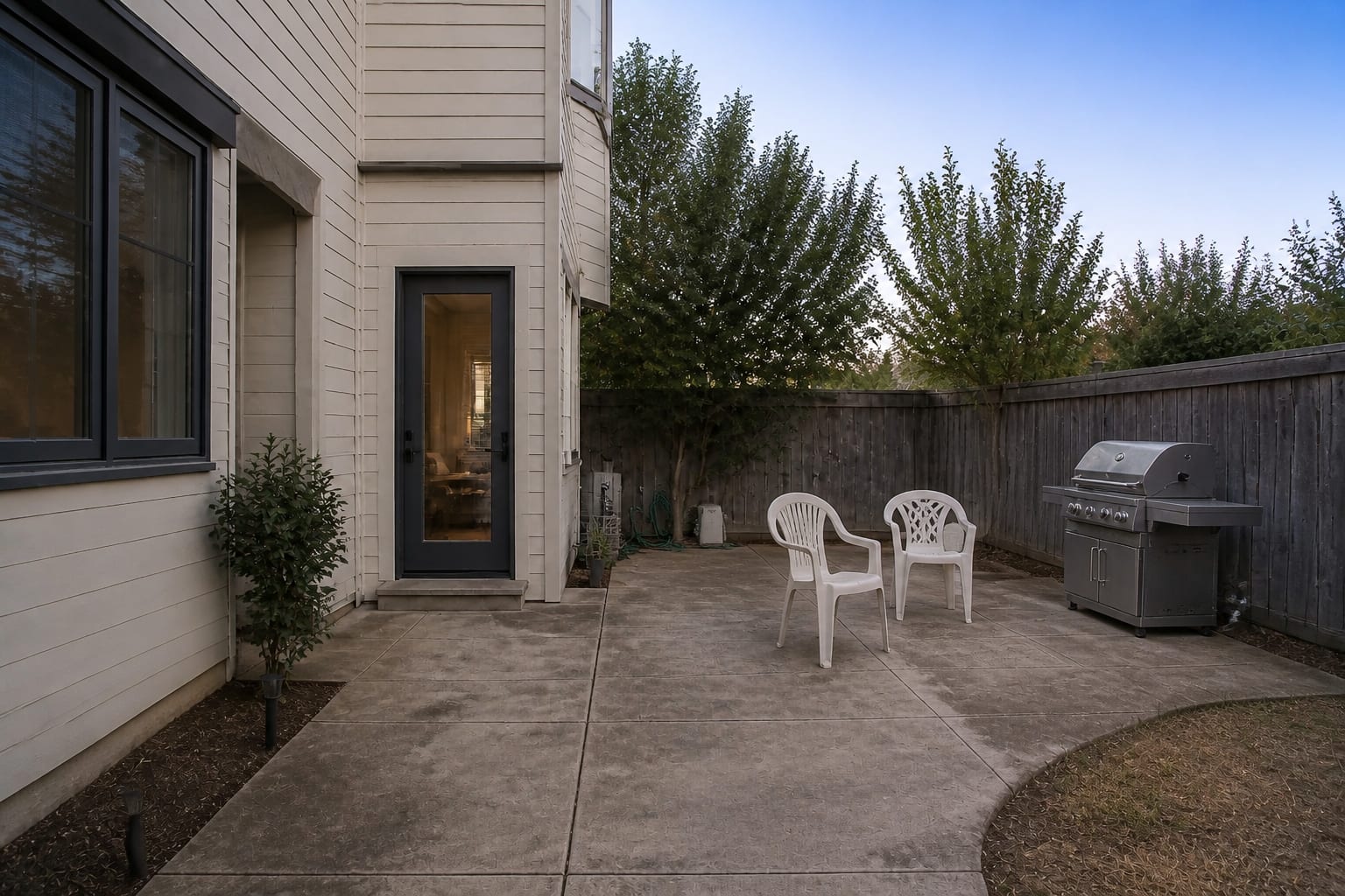 under designed patio with freestanding grill, empty concrete, scattered chairs, no prep surface, no shade, and a weak route from the house door.