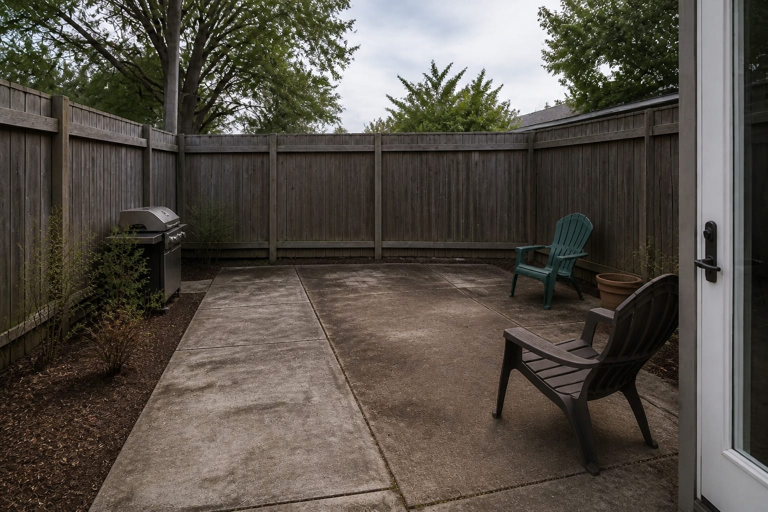 under designed patio with plain concrete, scattered chairs, exposed fence, no shade, and no clear furniture zone