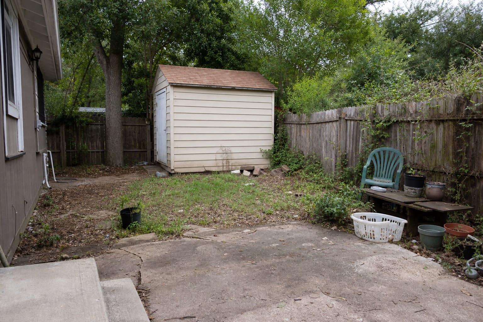 underused backyard shed with bare siding, uneven grass, clutter near the door, and no clear path or office identity.
