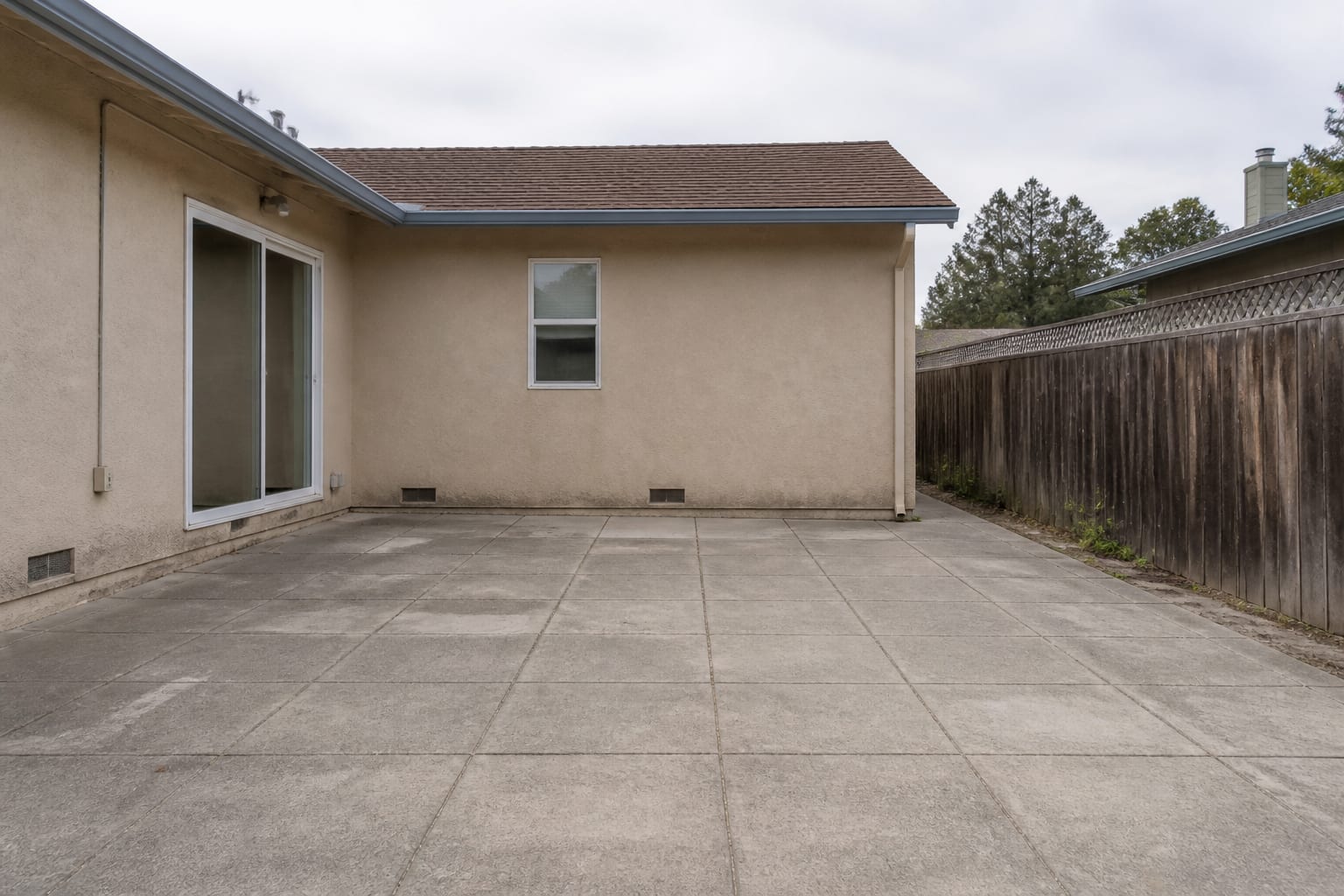 A plain empty concrete patio with bare walls, no furniture, and no plants
