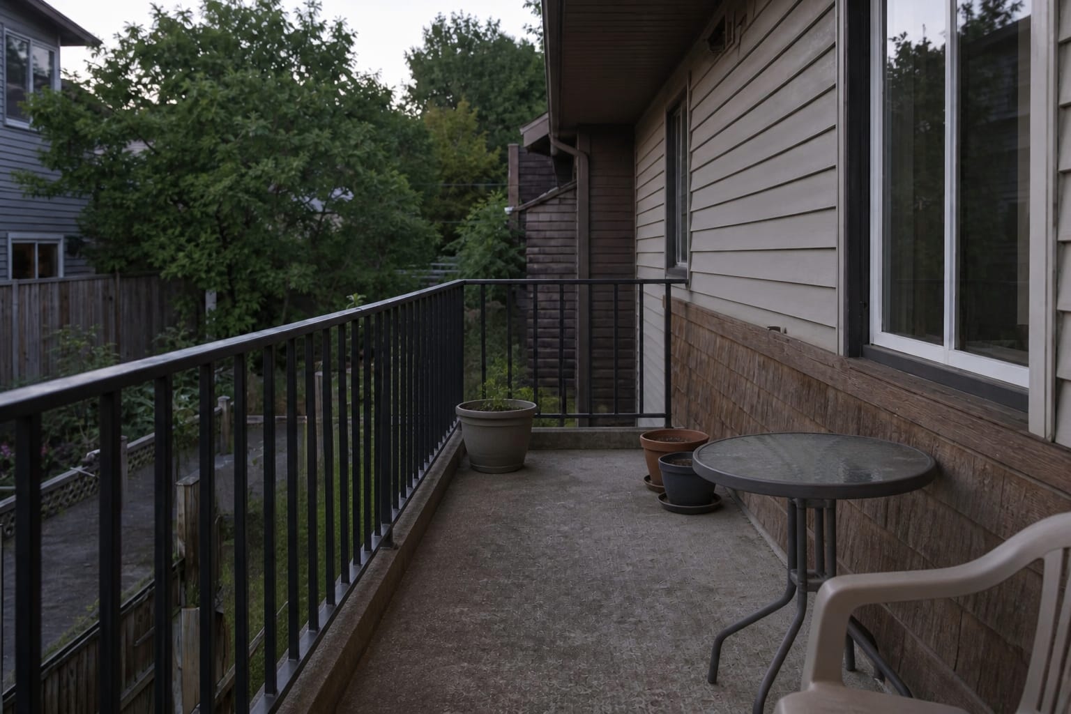 Narrow apartment balcony with a few small mismatched pots, bare railing, empty floor space, and no clear planting structure.