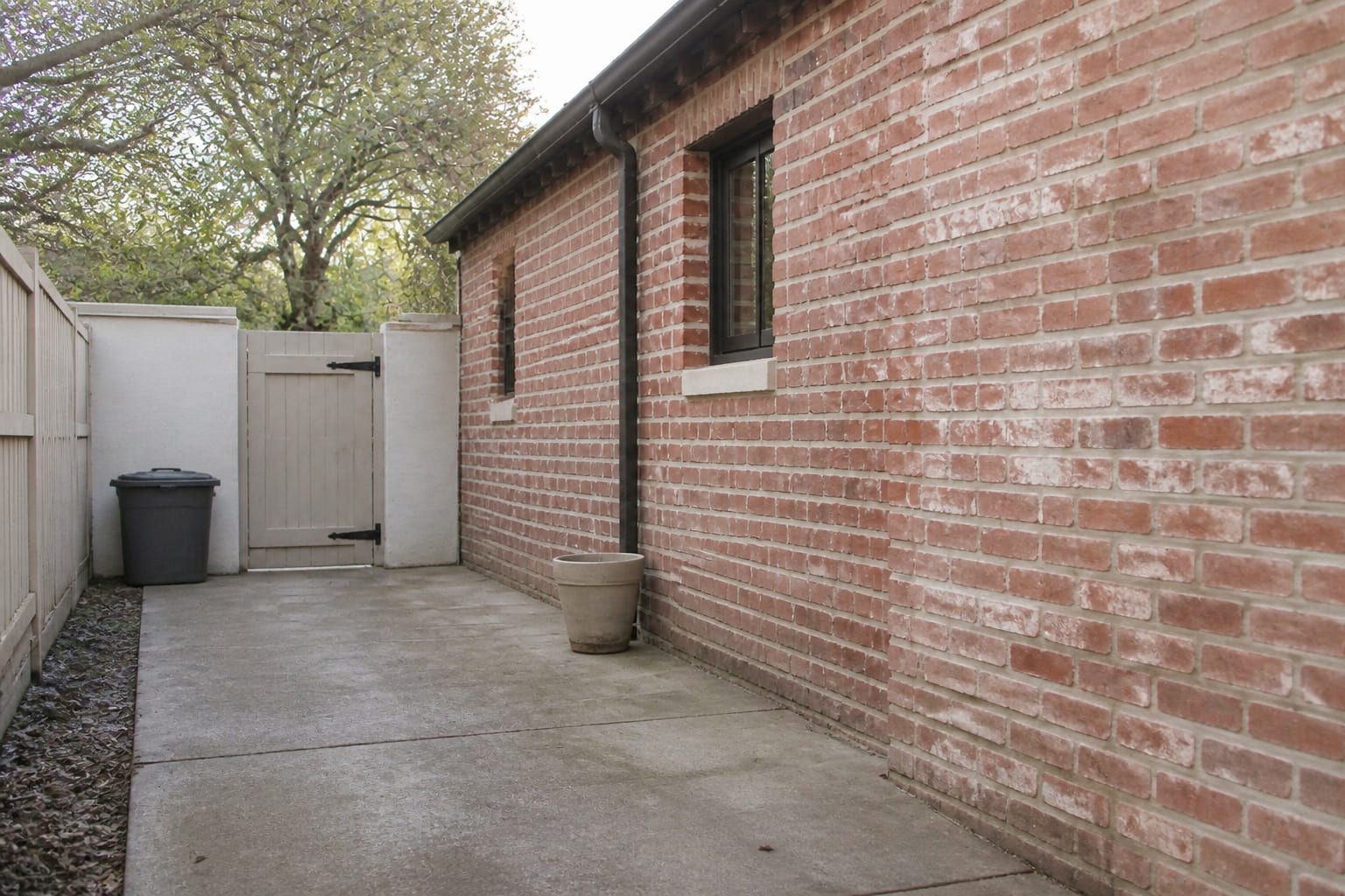A bare, uninviting concrete side yard with no plants, furniture, or enclosure features