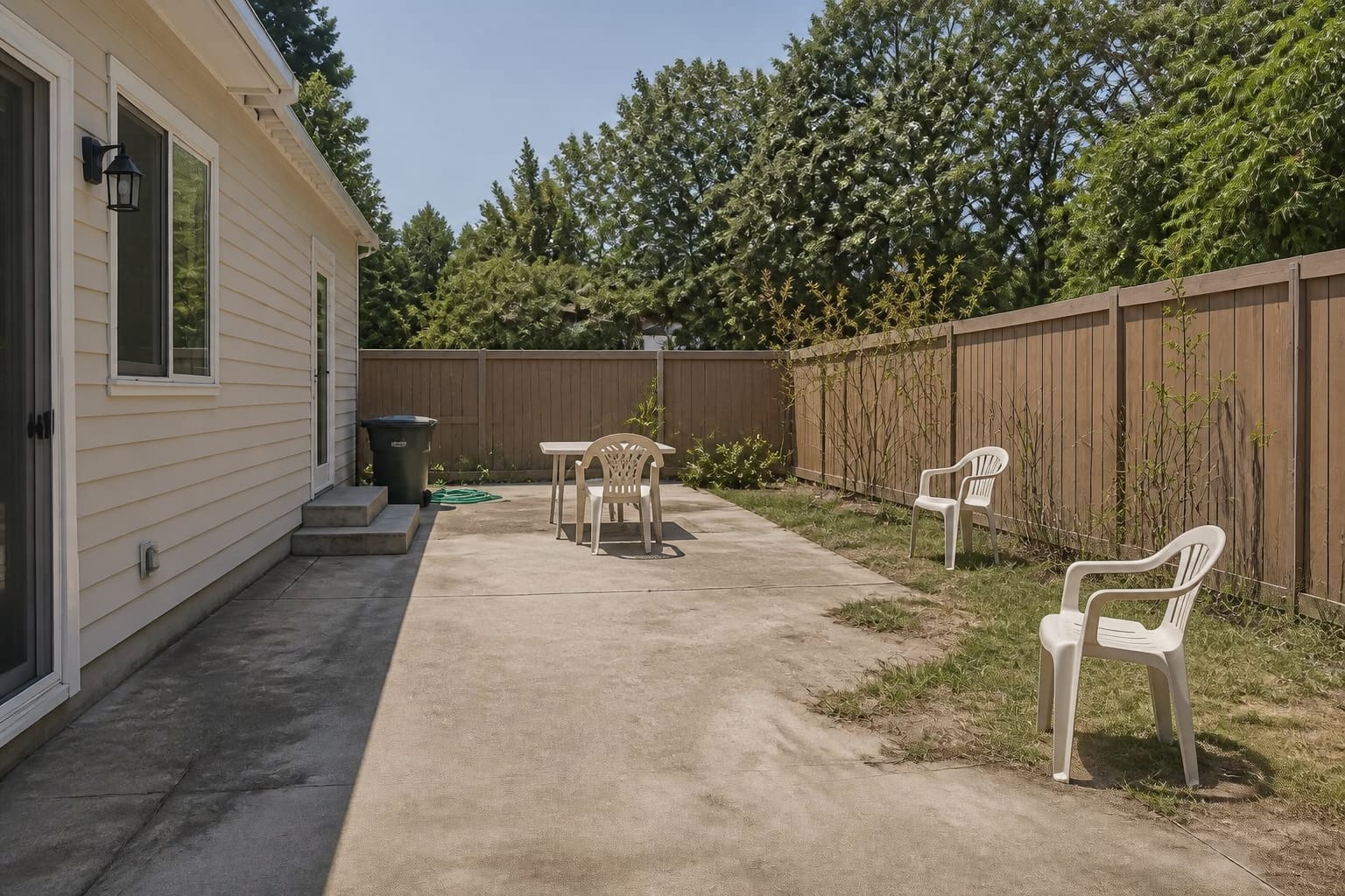 Exposed backyard patio with sun glare, scattered chairs, no shade structure, and furniture pushed awkwardly against the house.