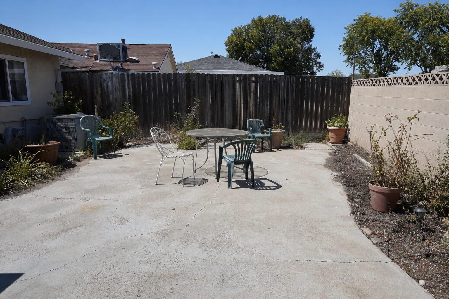 Exposed backyard patio with sun glare, scattered chairs, no shade structure, and furniture pushed awkwardly against the house.