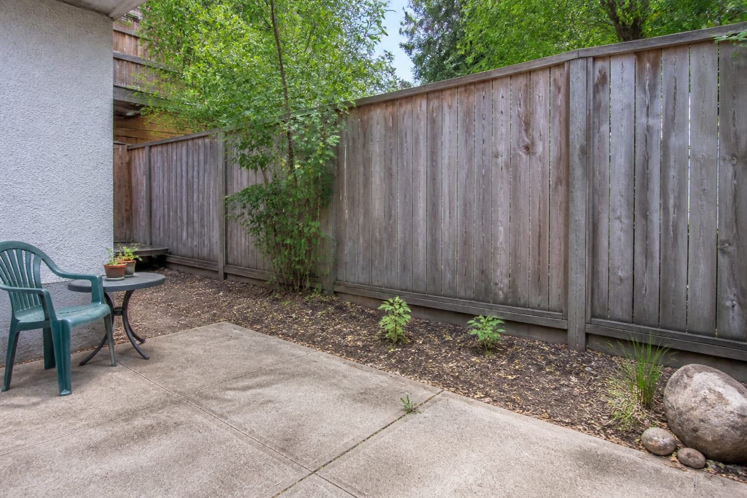 Sparse flat flower border with bare soil and a few scattered plants before redesign