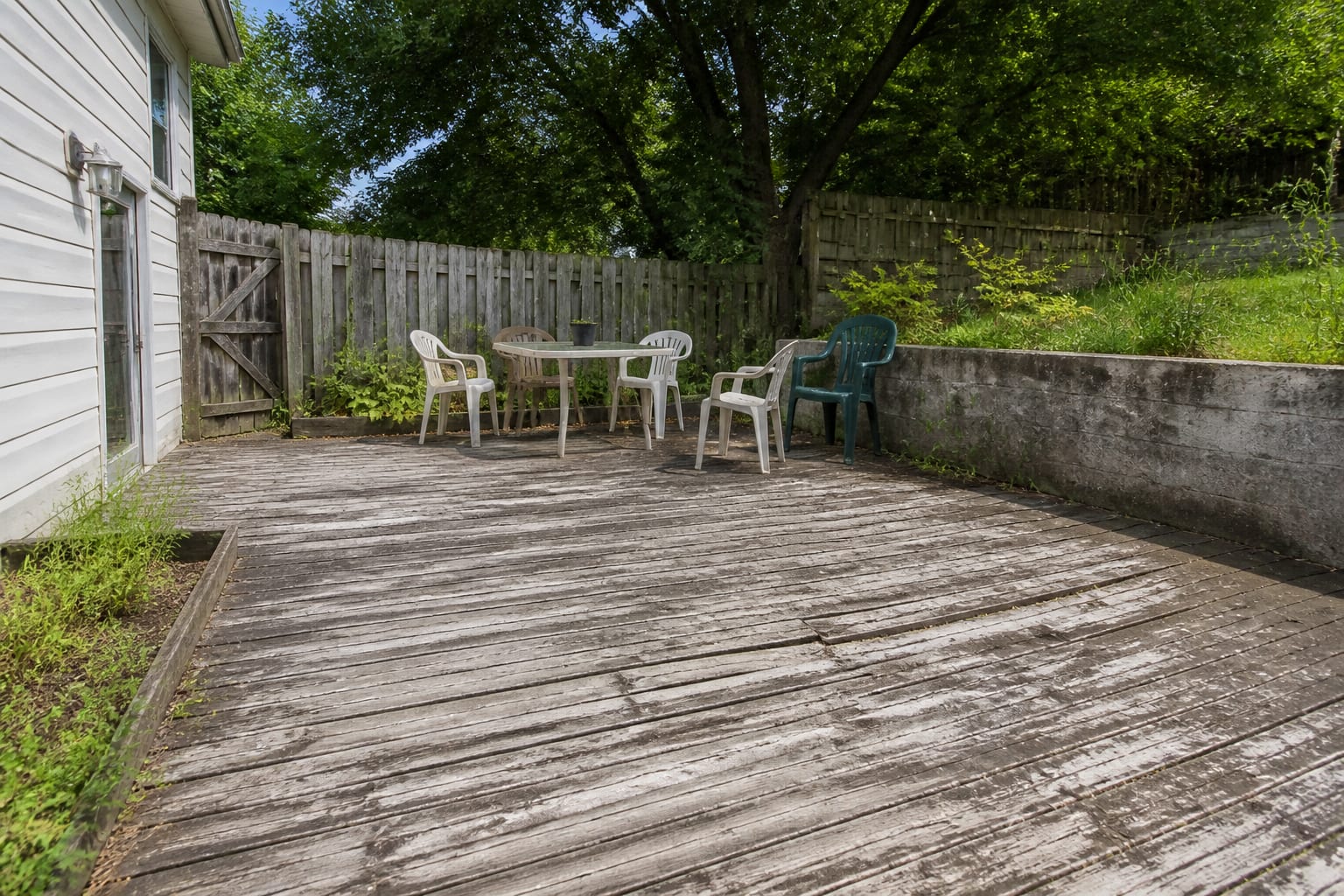 Weathered gray pressure-treated deck with cupped splintering boards and peeling stain before resurfacing
