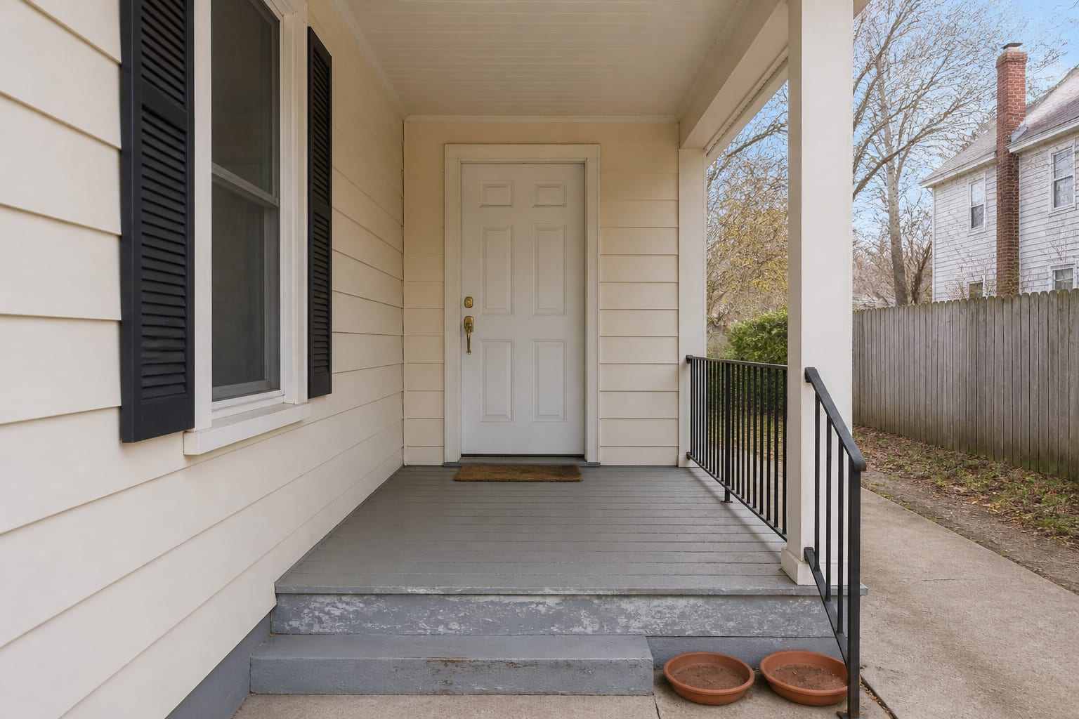Bare front porch with empty steps and a plain door before fall decorating