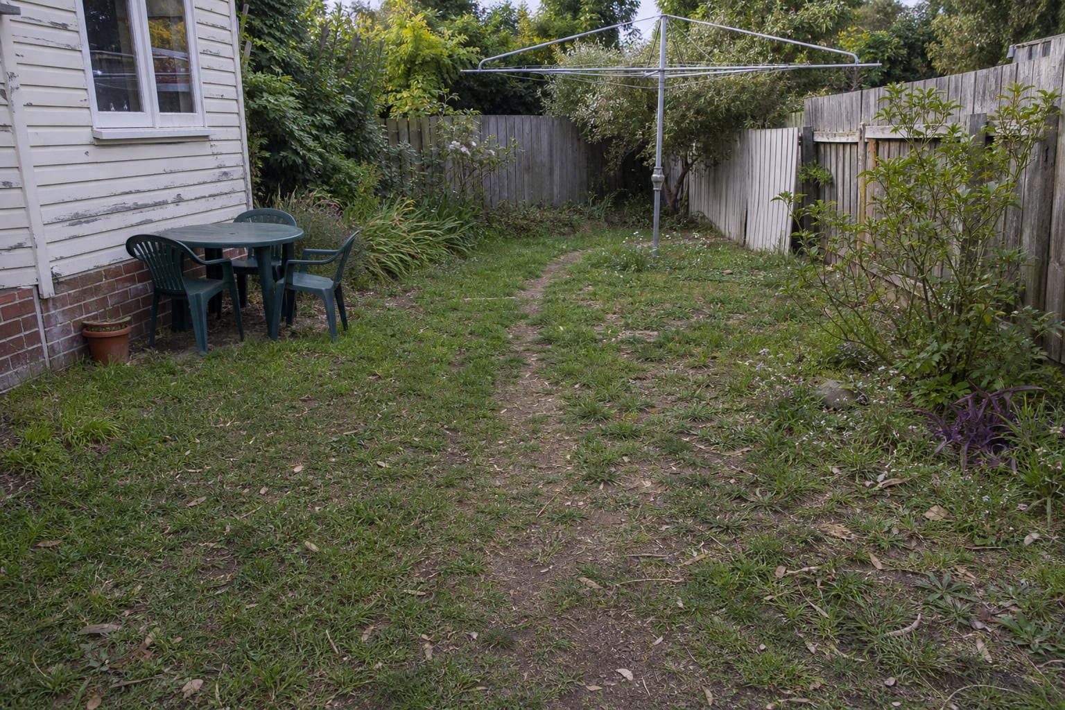 narrow muddy garden shortcut through patchy lawn with no defined path or planting edge