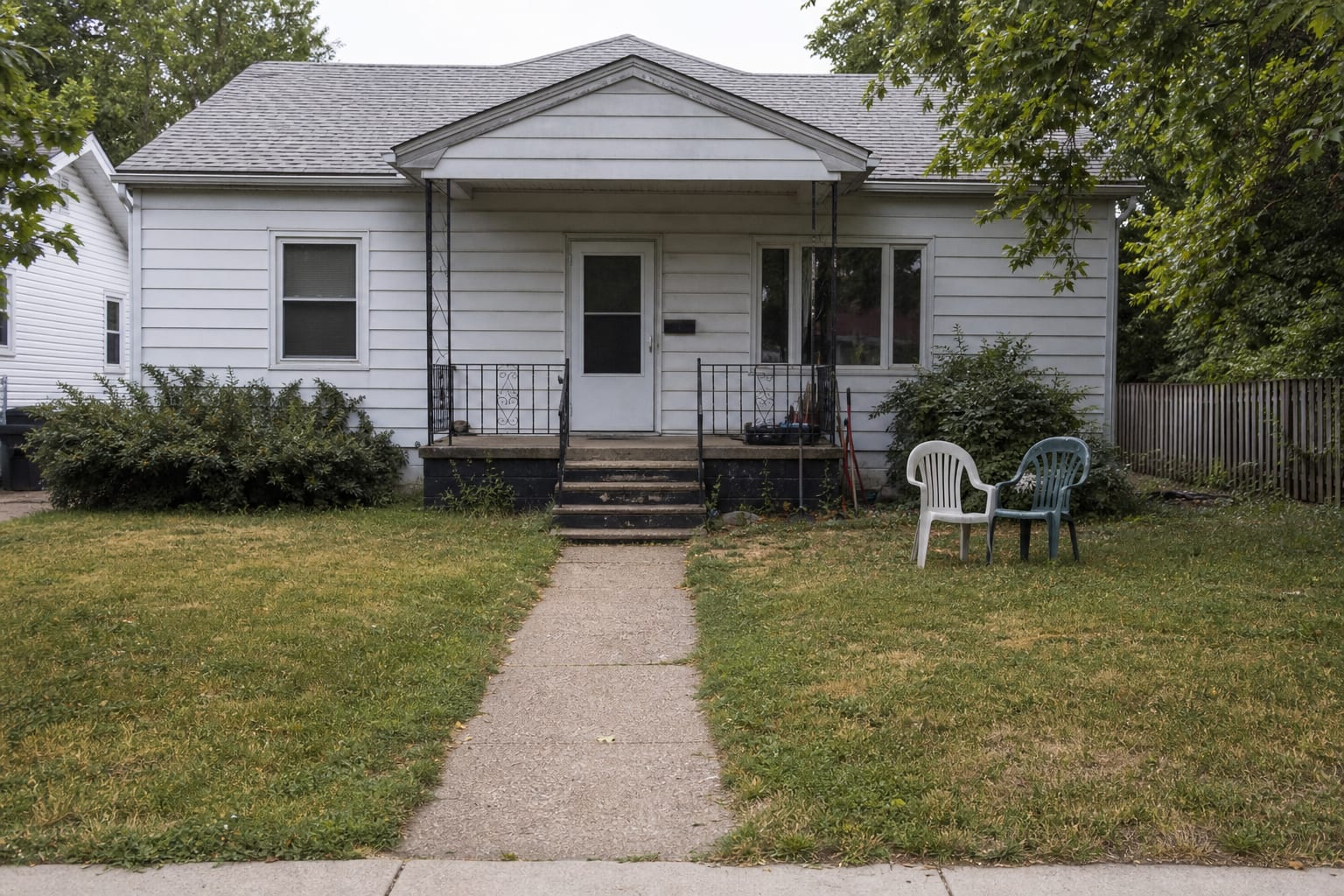 under designed front yard with thin lawn, narrow walkway, sparse shrubs, exposed foundation, and no lighting to guide visitors to the entry.