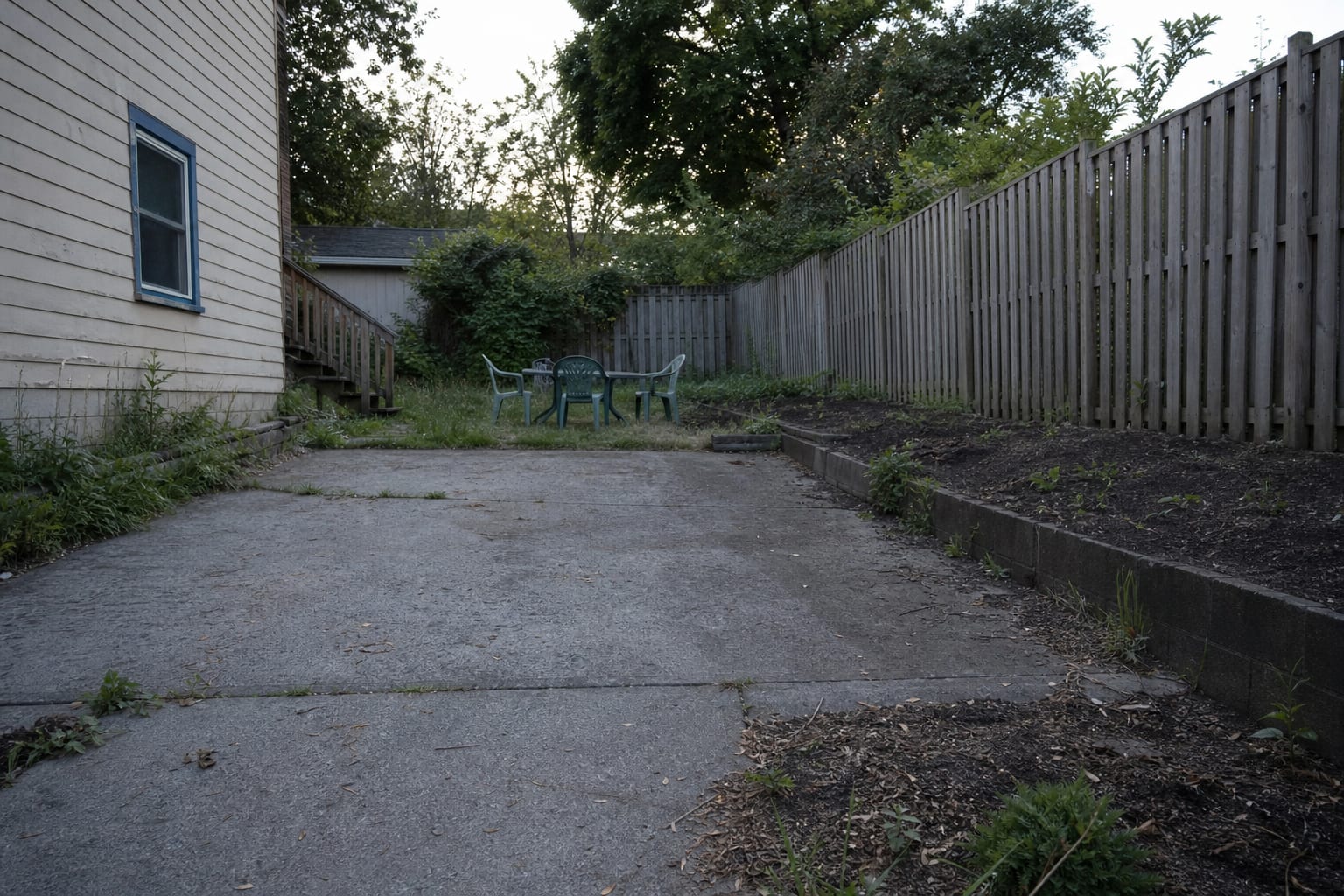 unlit garden path with dark planting beds, invisible steps, and a seating area disappearing into the yard after sunset