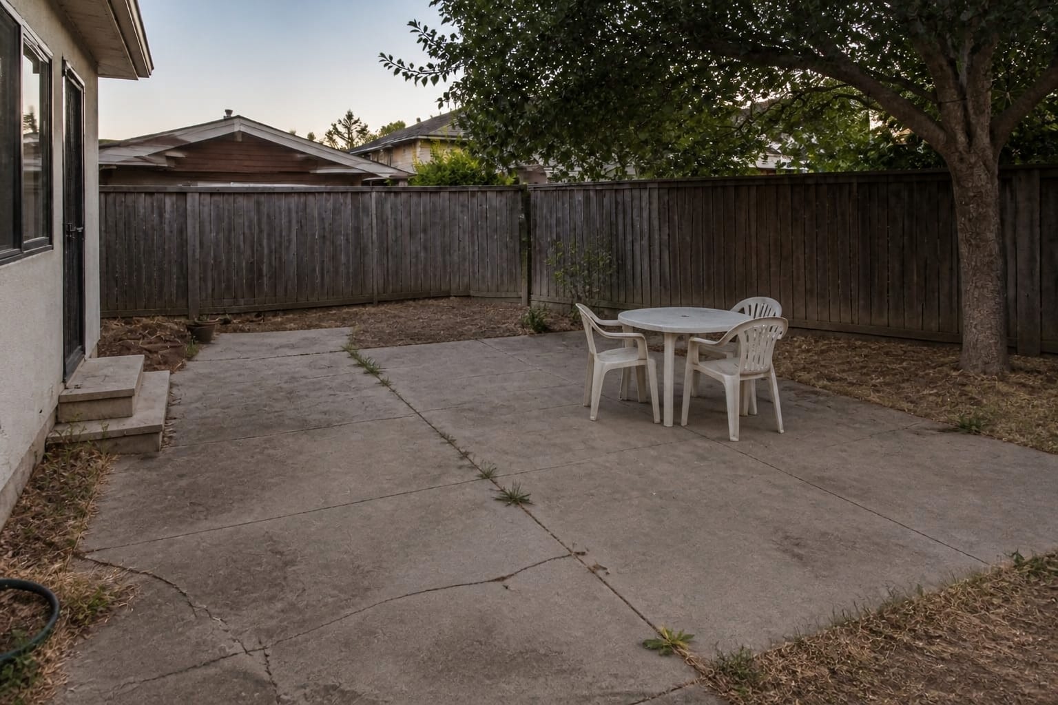 Over-paved backyard that is mostly hot bare concrete with no plants before landscape redesign