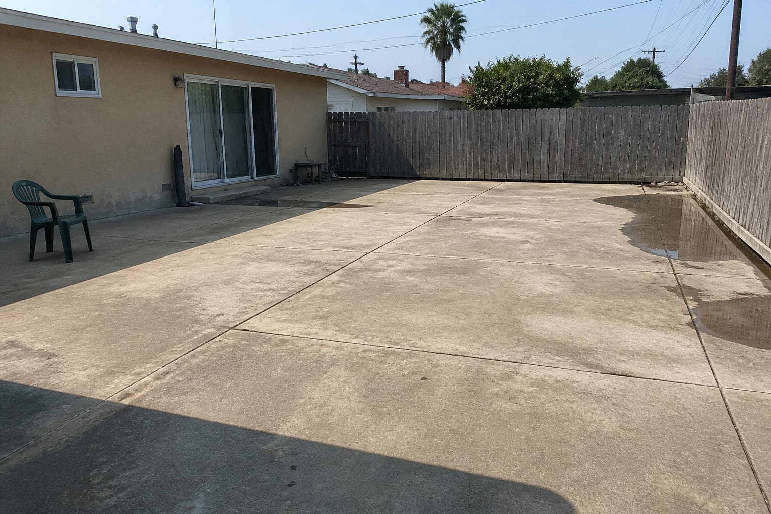 Over-paved backyard that is mostly hot bare concrete with no plants before landscape redesign