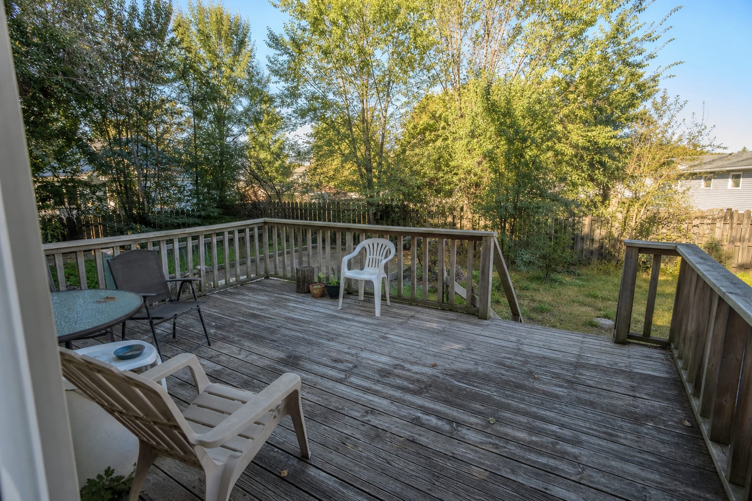 Sun-exposed backyard deck with aging boards, no coordinated material plan, and unfinished furniture placement.