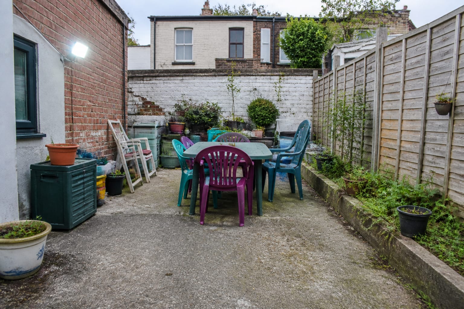 Cluttered suburban patio with bulky bright plastic furniture and scattered pots