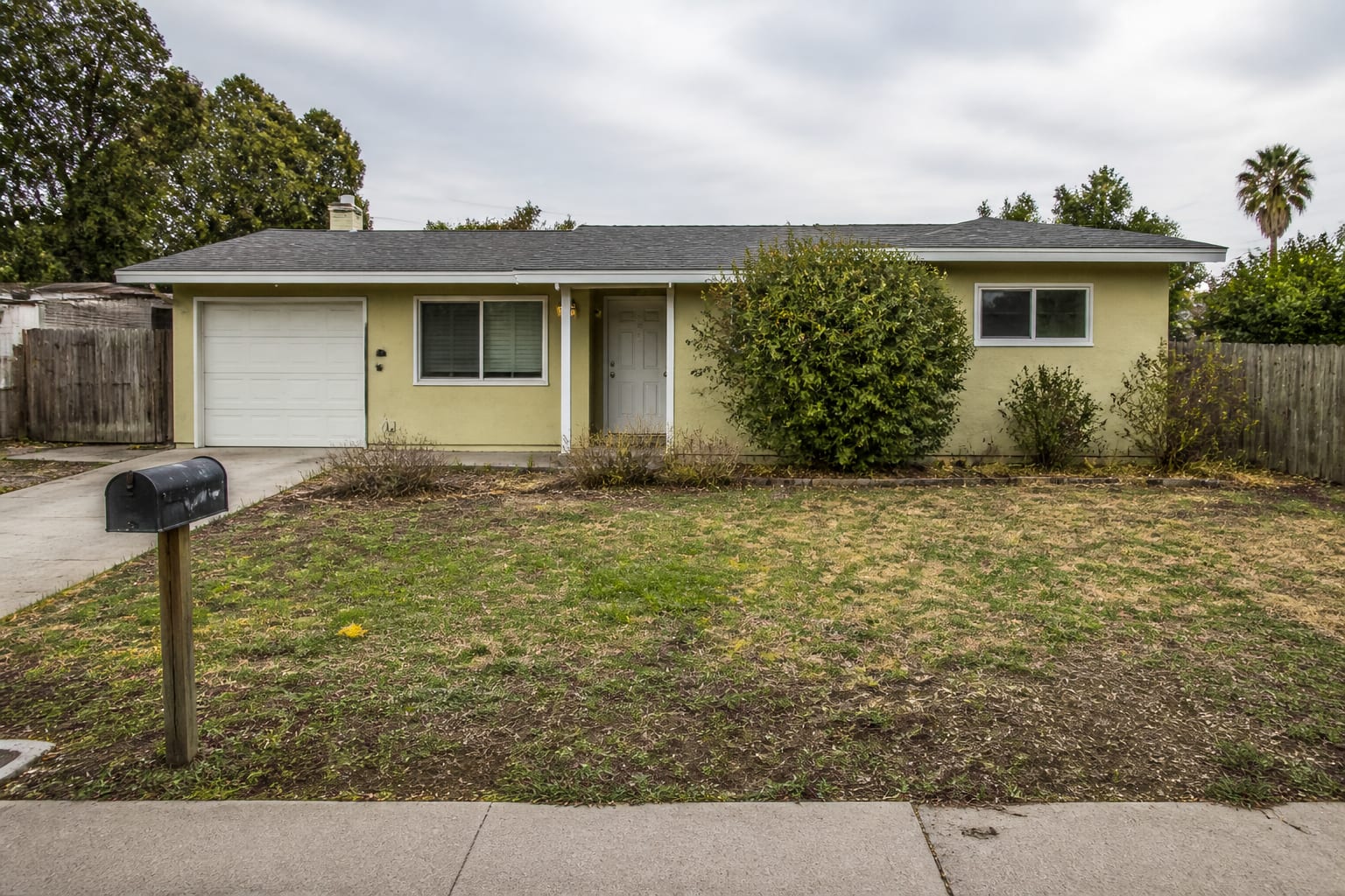 Bare front yard with patchy lawn and empty beds before landscaping