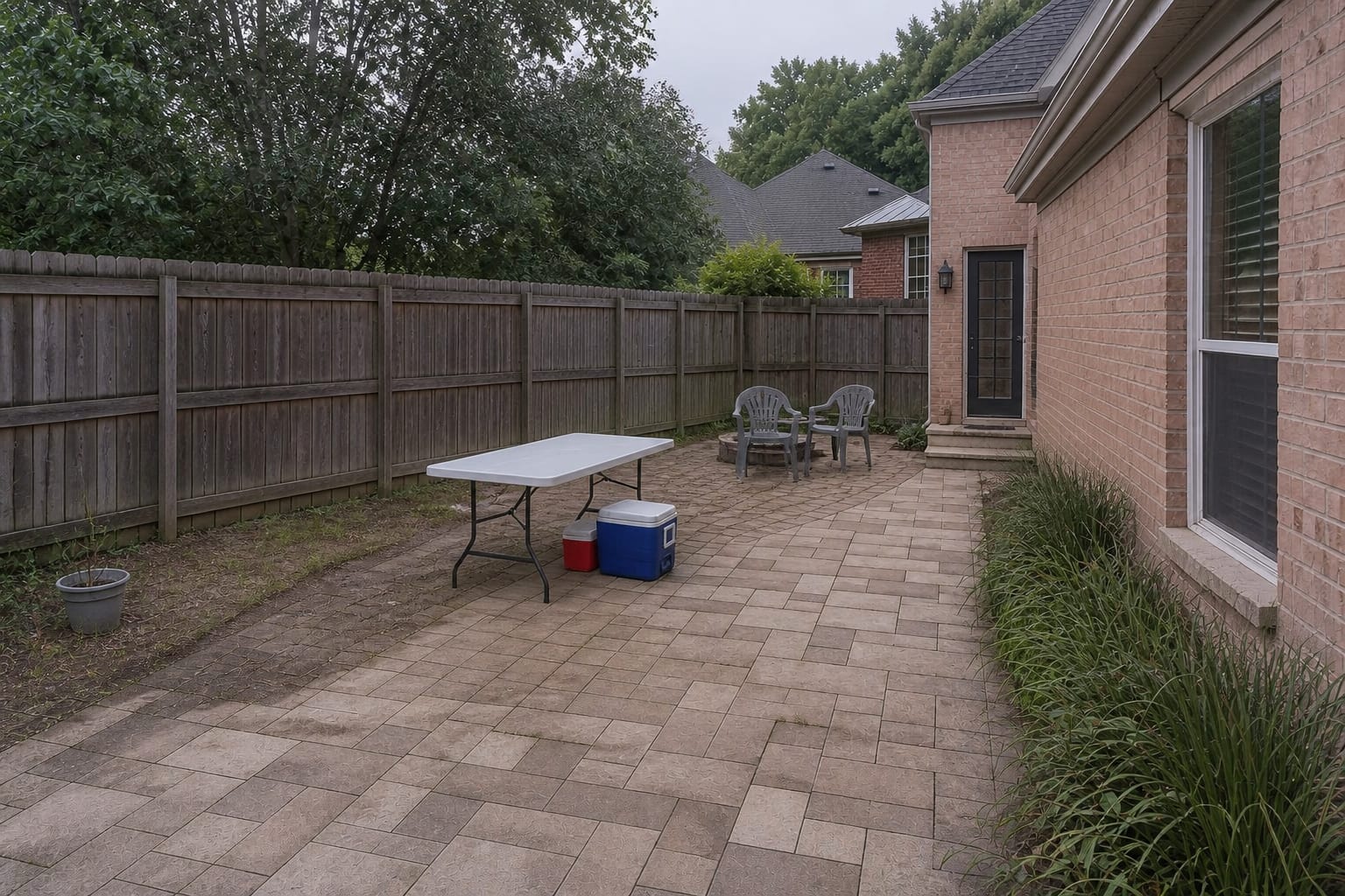 unplanned patio corner with a folding table, mismatched coolers, exposed fence, and no shade or serving counter