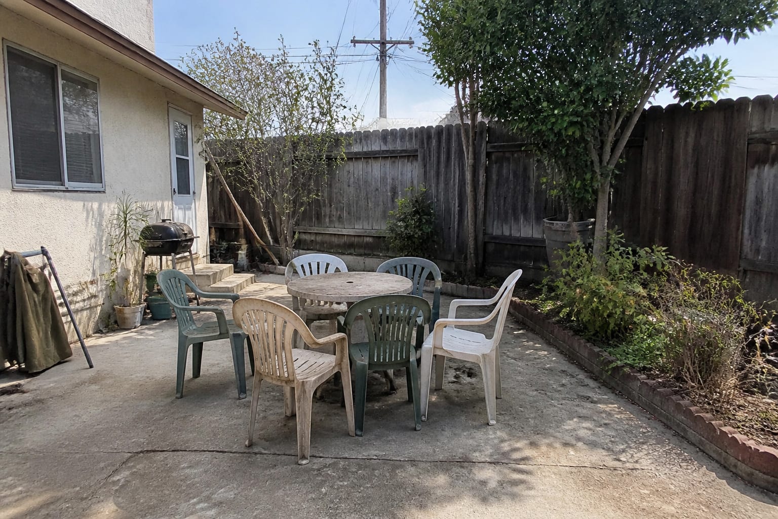 Cramped patio with mismatched plastic chairs around a small table before redesign