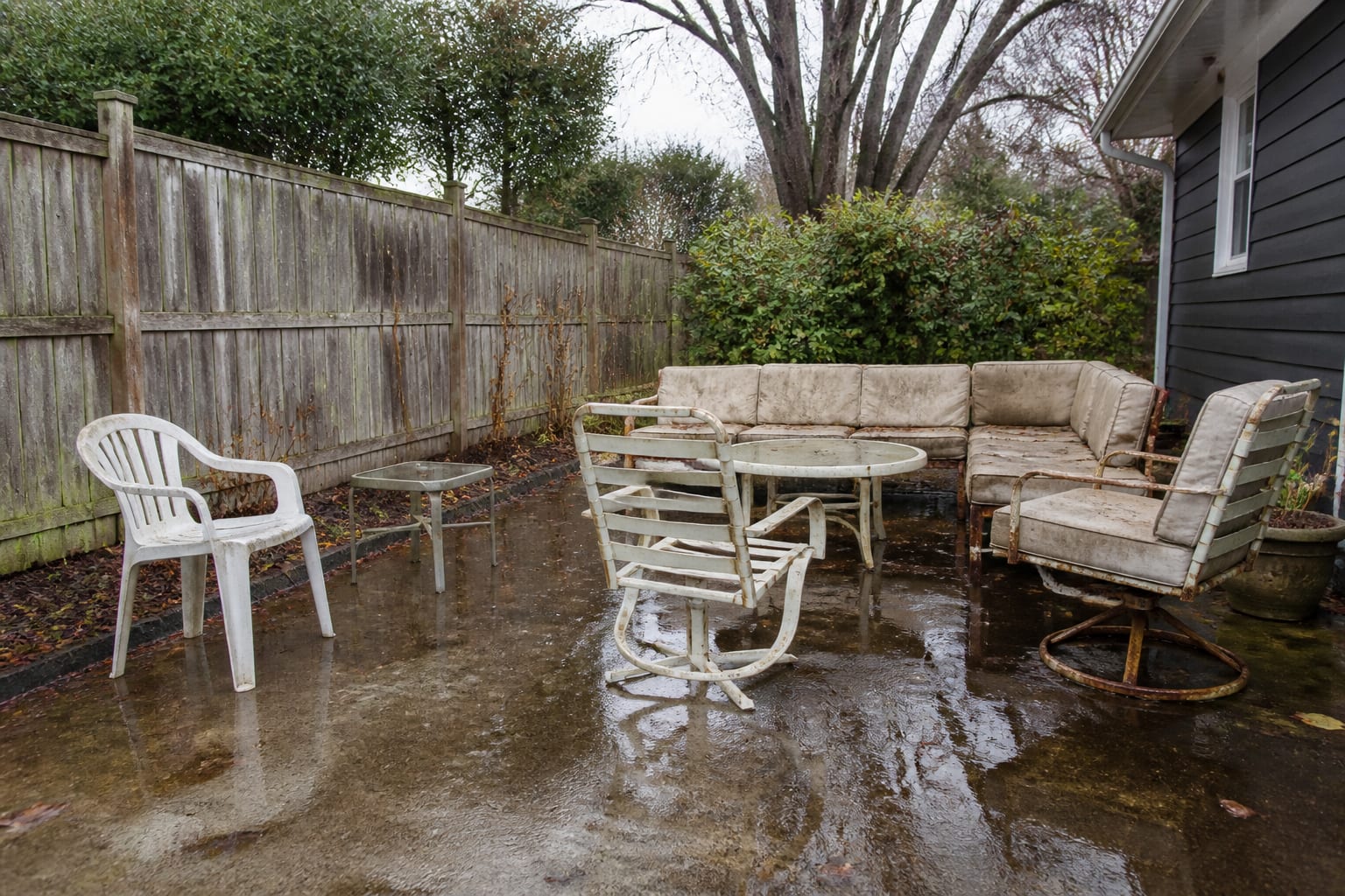 Patio furniture left uncovered and weathered with faded cushions and rusting legs before winter protection