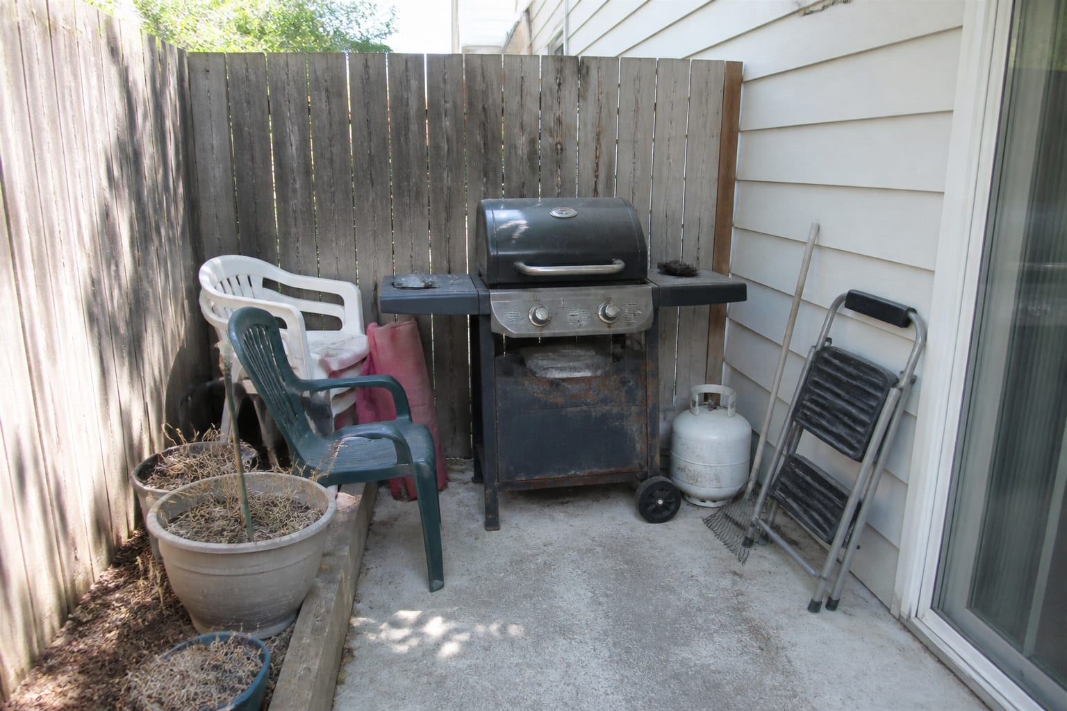 Cramped patio corner with a rusting freestanding propane cart grill and no counter or prep space before redesign