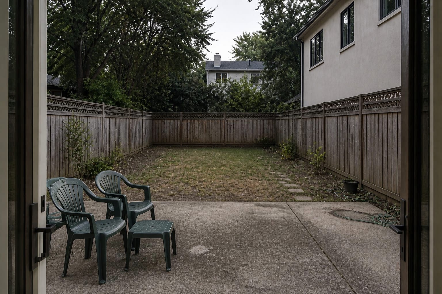 Open backyard with a large plain lawn, scattered chairs, exposed fence lines, and no defined dining or lounge zones.