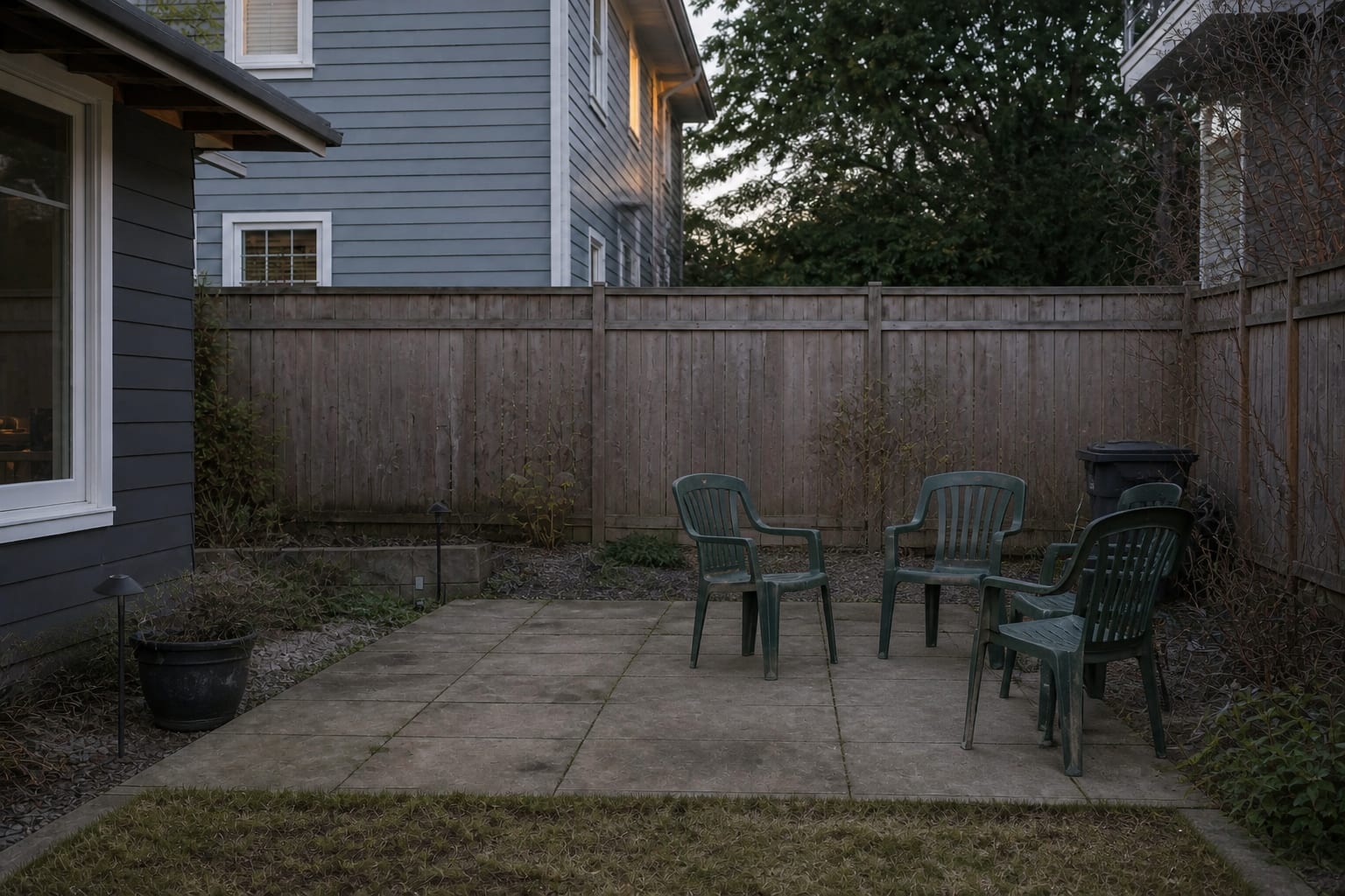 Bare patio corner with scattered outdoor chairs, no sofa, no shade, and no usable side surfaces for drinks or books.