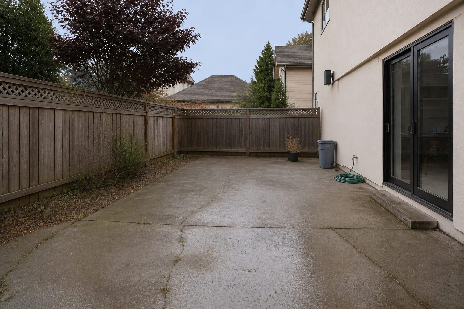 Cracked stained concrete patio with weeds in the joints and a slick polished surface before retiling