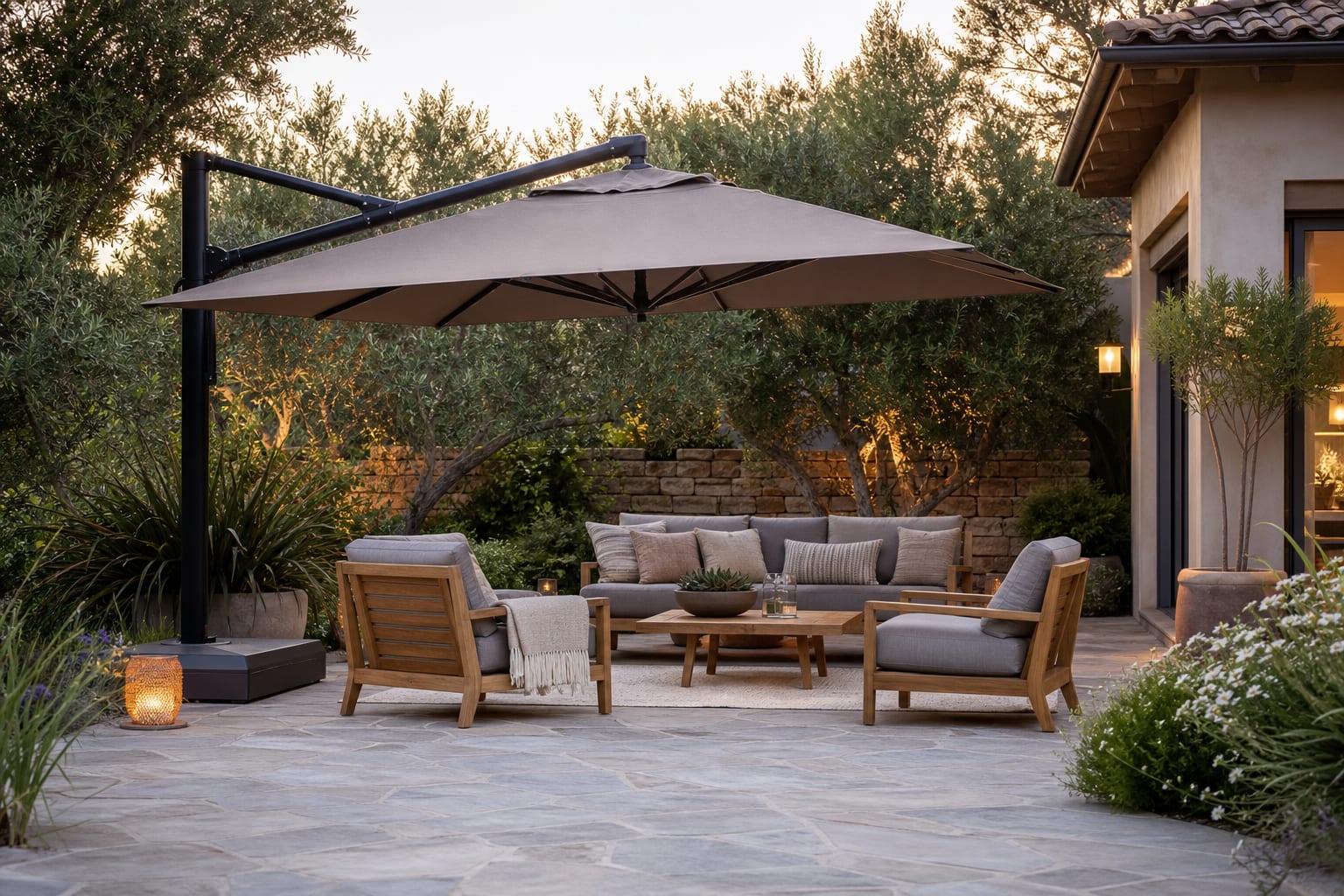 large taupe cantilever umbrella shading a patio lounge with stone pavers, teak chairs, and clear walking space