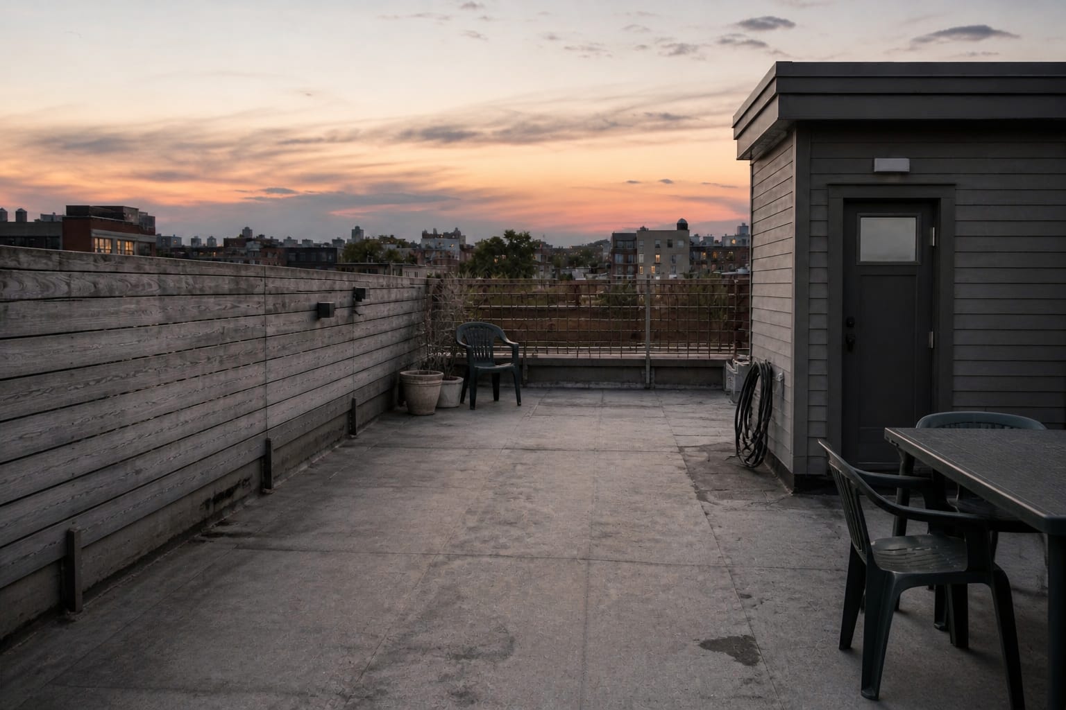 plain rooftop access area with bare waterproofing, exposed railings, scattered chairs, no shade, and no defined seating zone