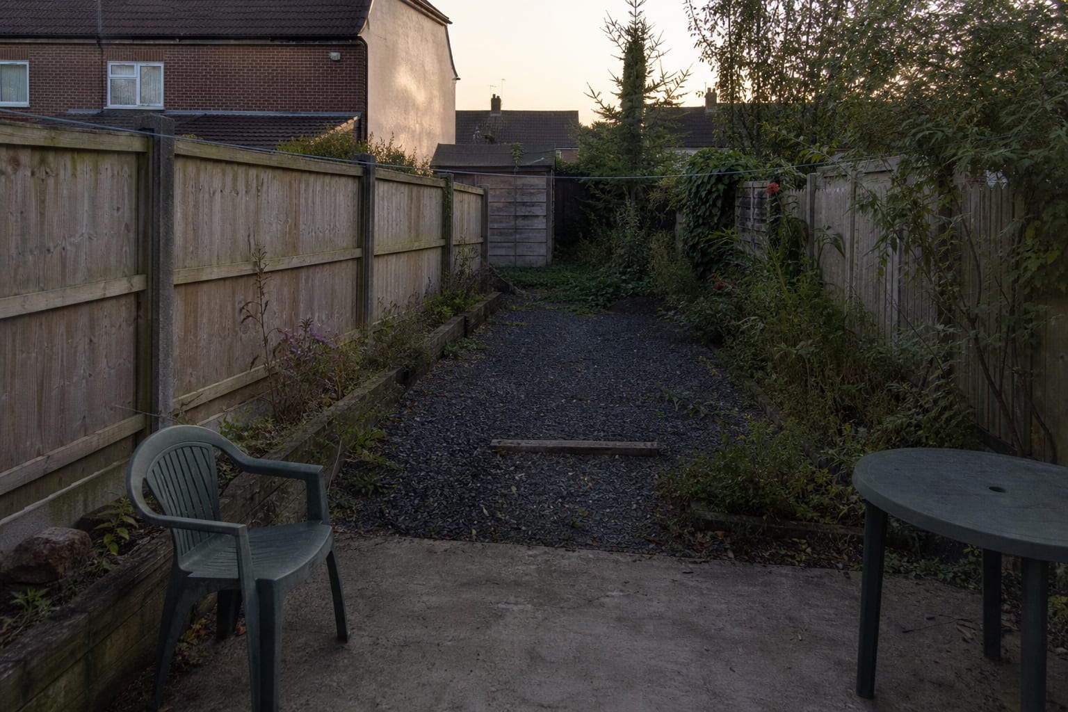 An underlit garden path with dark planting beds, an unmarked step, and a patio that disappears after sunset.