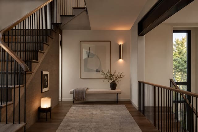 staircase landing with a slim bench, framed art, warm wall sconce, and clear path between the stair flights