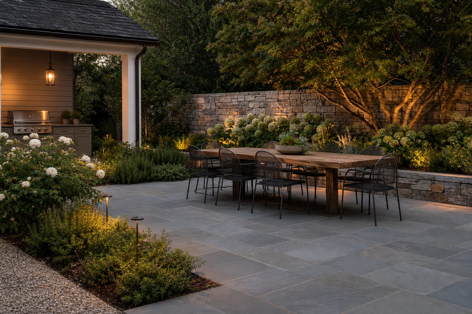 rectangular bluestone patio pattern with narrow joints, gravel base edge, and planting beds around a dining area