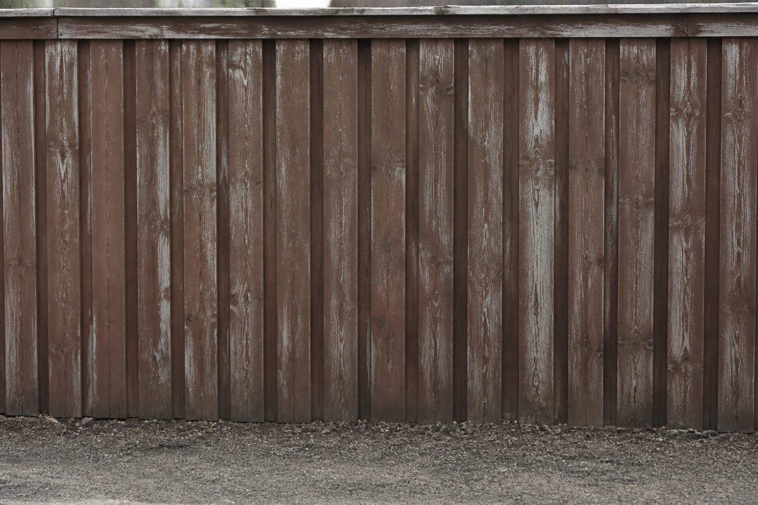 A plain wooden fence with peeling paint and no planting, looking bare and utilitarian