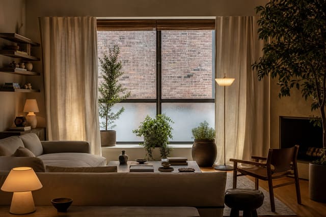 soft linen curtain, frosted lower glass, and plants framing a window that faces a warm brick wall outside