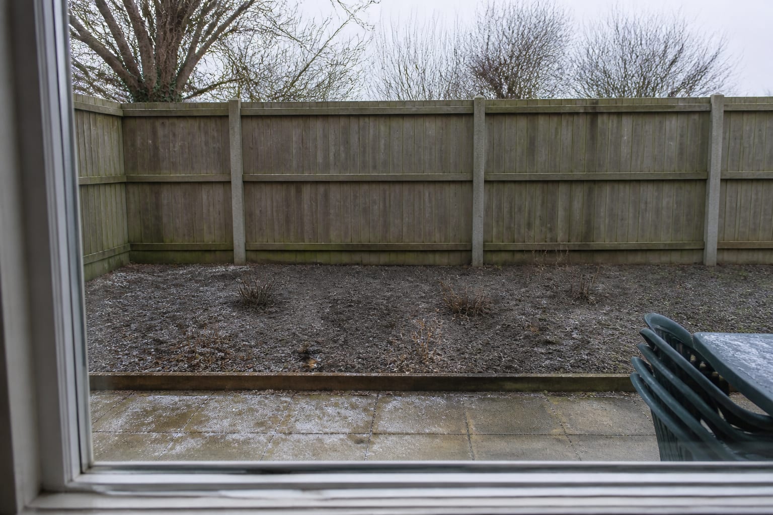 A bare, lifeless winter garden border with empty soil and no structure
